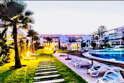 a resort with a swimming pool and lounge chairs at Appartement Blanca Beach in Sidi Rahal