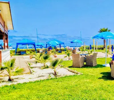 a patio with chairs and umbrellas on the beach at Appartement Blanca Beach in Sidi Rahal