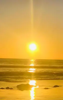 a sunset over the ocean with the sun setting at Appartement Blanca Beach in Sidi Rahal