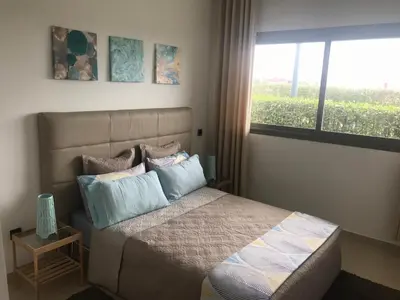 a bedroom with a bed with pillows and a window at Appartement Blanca Beach in Sidi Rahal