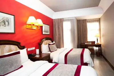 a hotel room with two beds and a red wall at Hôtel Les Saisons in Casablanca