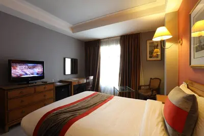 a hotel room with a bed and a television at Hôtel Les Saisons in Casablanca