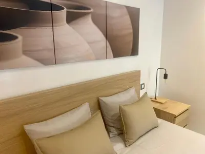 a bed with two pillows and a picture of vases at Appartement les pieds dans l'eau WELCOME STAY in Mohammedia