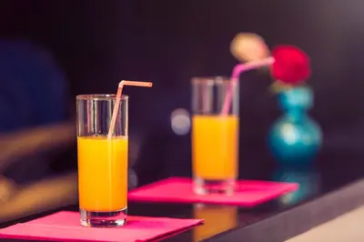 two glasses of orange juice sitting on pink napkins at Casablanca Home Stay Apartment in Casablanca