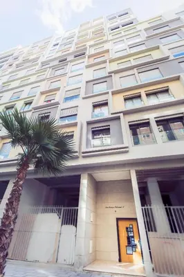 a building with a palm tree in front of it at Casablanca Home Stay Apartment in Casablanca