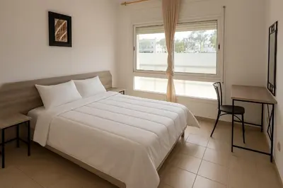 a bedroom with a bed and a desk and a window at Appartement Hay Riad in Rabat