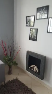 a living room with a fireplace with pictures on the wall at Residence les Pins in Rabat