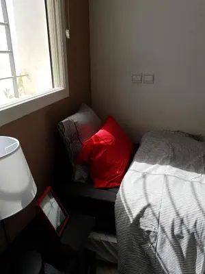 a bedroom with a bed with red pillows and a window at Residence les Pins in Rabat