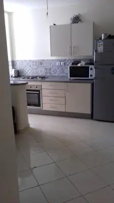 a kitchen with white appliances and a white tile floor at Appartement Tamaris couple mariés in Tamaris