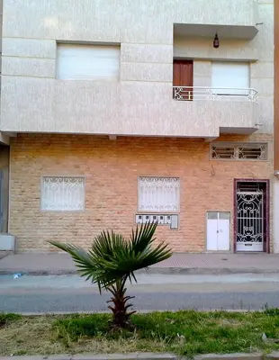 a building with a palm tree in front of it at Joudia in Temara