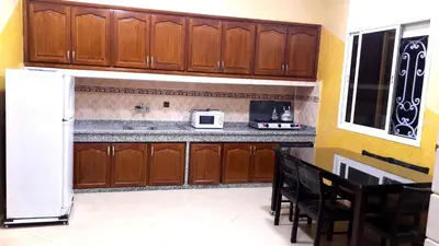 a kitchen with wooden cabinets and a white refrigerator at Joudia in Temara