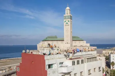 a mosque with a clock tower on top of a building at Res Mario 3 Lovely Apartment With Balcony & Sea View Free Wifi in Casablanca