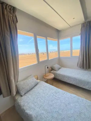 a bedroom with two beds and windows with a view at Résidence Evasion in Bouznika