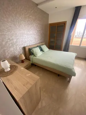 a bedroom with a bed and a wooden table at Résidence Evasion in Bouznika