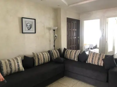 a living room with a black couch with pillows at Familly Apartement Agdal Rabat centre in Rabat