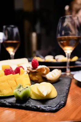 a plate of fruit on a table with two glasses of wine at Hôtel du Golf Mohammedia in Mohammedia