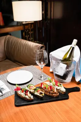 a table with a plate of food and a bottle of wine at Hôtel du Golf Mohammedia in Mohammedia