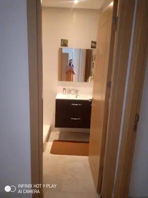 a bathroom with a sink and a person in a mirror at residance a 100 m de la mer in El Harhoura