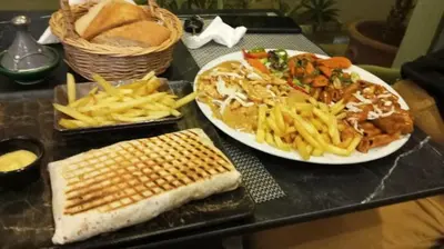 a table with two plates of food and french fries at Nouaceur Garden Comfort and Serenity Casa Airport in Nouaseur