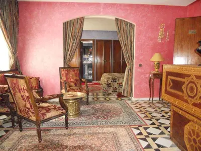 a living room with pink walls and a room with chairs at Hôtel Transatlantique in Casablanca