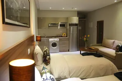 a living room with two beds and a kitchen at L'escale Suites Résidence Hôtelière By 7AV HOTELS in Mohammedia