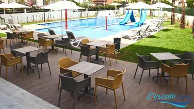 a restaurant with tables and chairs next to a pool at L'escale Suites Résidence Hôtelière By 7AV HOTELS in Mohammedia