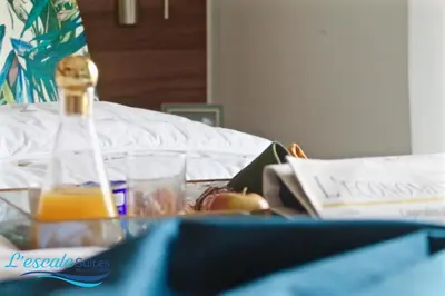 a bed with a bottle of orange juice and a book at L'escale Suites Résidence Hôtelière By 7AV HOTELS in Mohammedia