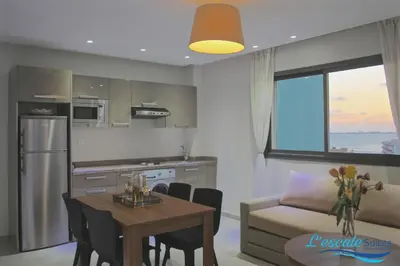 a kitchen and living room with a table and a couch at L'escale Suites Résidence Hôtelière By 7AV HOTELS in Mohammedia