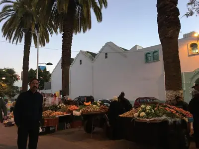 a man standing in front of a market with fruits and vegetables at Appartement Cosy - Corniche plage Mohammedia in Mohammedia