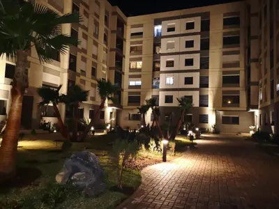 a building at night with palm trees in the courtyard at Luxury résidence Taj Nouaceur in Nouaseur