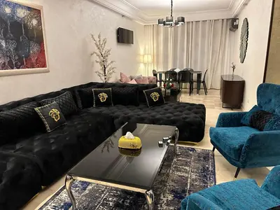 a living room with a black leather couch and blue chairs at Appartement Casablanca vue sur mer in Casablanca