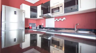a large kitchen with red walls and stainless steel appliances at Luxueux Appart Au Triangle D'Or Casablanca in Casablanca