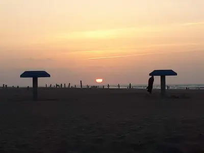 a sunset on the beach with umbrellas in the sand at Dream House Sidi Rahal Beach in Sidi Rahal
