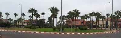 a roundabout with palm trees and buildings in a city at Dream House Sidi Rahal Beach in Sidi Rahal