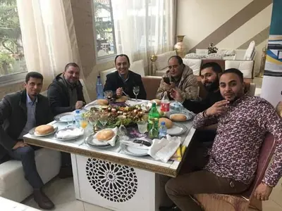 a group of men sitting around a table with food at reda land in O Ben Slimane