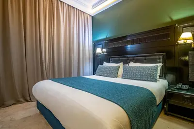 a bedroom with a large bed with blue and white pillows at Diwan Casablanca Hotel & Spa in Casablanca