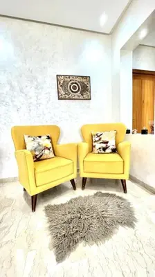 two yellow chairs and a rug in a living room at Taj nouaceur aéroport Mohamed V in Nouaseur
