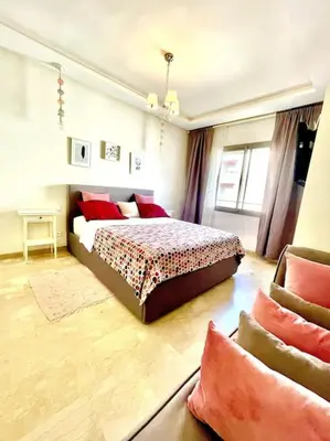 a bedroom with a bed with red pillows on it at Taj nouaceur aéroport Mohamed V in Nouaseur
