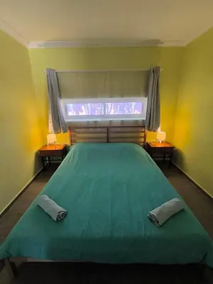 a bedroom with a green bed and a window at Palm Grove Farm in Tit Mellil