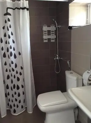 a bathroom with a toilet and a shower curtain at Palm Grove Farm in Tit Mellil