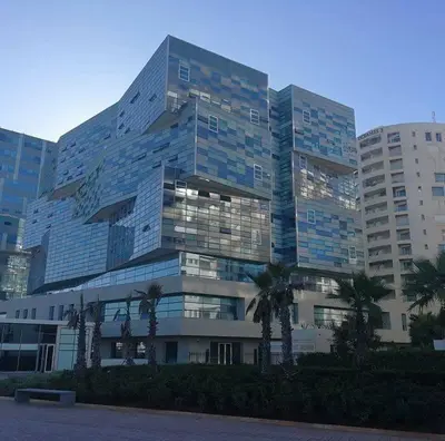 a large glass building with palm trees in front of it at luxury apartment in Marina Casablanca in Casablanca