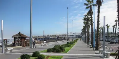 a sidewalk with palm trees and a gazebo on a beach at luxury apartment in Marina Casablanca in Casablanca
