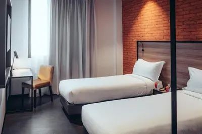 a hotel room with two beds and a chair at ONOMO Hotel Casablanca Sidi Maarouf in Casablanca