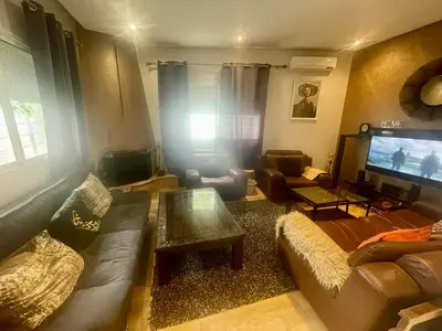 a living room with a couch and a tv at Au Cœur Des Plages de Rabat in Oulad Kerroum