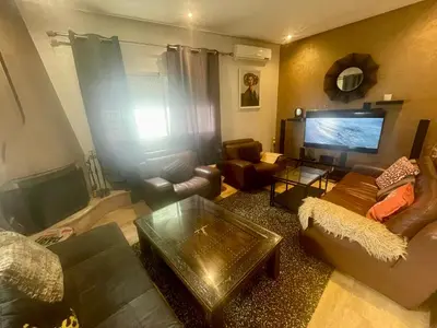a living room with a couch and a tv at Au Cœur Des Plages de Rabat in Oulad Kerroum