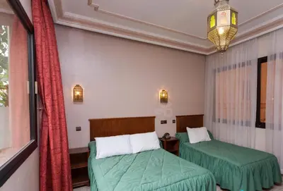 a room with two beds and a window at Hôtel Astrid in Casablanca