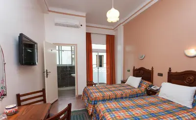 a hotel room with two beds and a table at Hôtel Astrid in Casablanca