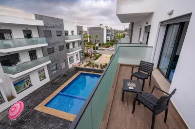an apartment balcony with a swimming pool and two chairs at Garden Bay Appart'Hôtel in Casablanca