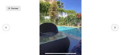 a person sitting in a chair next to a swimming pool at Villa moderne avec piscine, front de mer in Casablanca