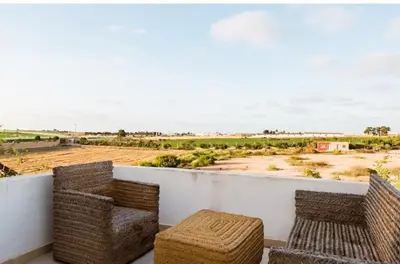 a balcony with wicker chairs and a view of a field at Elaaz Horse Farm in Azemmour